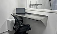 Interior of a white containerized structure, featuring a stainless steel desk with a touchscreen monitor